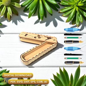 Könnte beinhalten: Ein helles Holz-Stifteetui mit Klappdeckel, lasergraviert mit einem Bleistift und anderen Designs. Das Etui ist geöffnet und gibt den Innenraum frei. Mehrere Stifte und Bleistifte werden neben dem Etui angezeigt. Die Worte "DIGITALER DOWNLOAD" sind sichtbar.