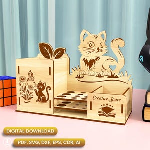 Op de afbeelding: Een houten bureau-organizer met een katten thema. De organizer heeft lasergesneden ontwerpen van een kat, bloemen en bladeren. Het heeft vakken voor pennen en potloden, en de woorden "Creative Space" zijn zichtbaar. De organizer is gemaakt van lichtgekleurd hout.