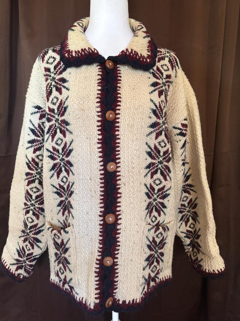 Puede incluir: C&aacute;rdigan color crema con botones y tejido texturizado. El su&eacute;ter presenta un cuello y ribete azul marino oscuro, con un patr&oacute;n de copo de nieve burdeos y azul marino. Tiene dos bolsillos y botones de madera.