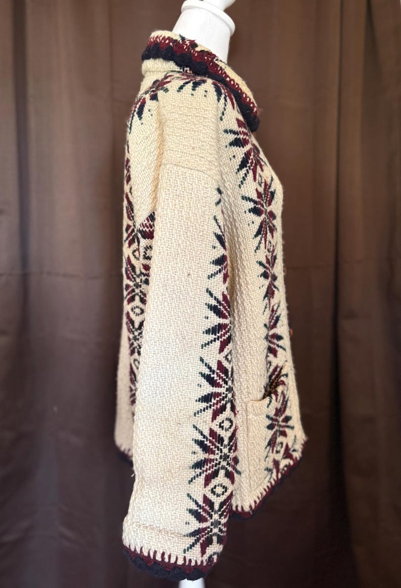 Puede incluir: Jersey de punto color crema con cuello alto y mangas largas. El jersey presenta un estampado de copos de nieve en azul marino, burdeos y verde. El cuello y los pu&ntilde;os est&aacute;n ribeteados con punto azul marino oscuro y burdeos.