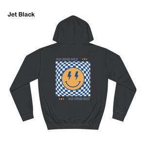 Op de afbeelding: Zwarte hoodie met capuchon. De achterkant heeft een vierkant ontwerp met een blauw-wit geblokt patroon, een gele smiley met bliksemschichtogen en de tekst "GAY VIBES ONLY".