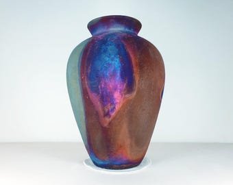 May include: A iridescent ceramic vase with a rounded body and a narrow neck. The vase has a blue, purple, and brown color scheme.