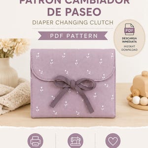Puede incluir: Un cambiador de pañales de color lavanda con un estampado floral blanco y un lazo de cinta morado oscuro. La imagen incluye el texto: munestpattern, SEWING PATTERNS, EASY BEGINNER FRIENDLY, PATRÓN CAMBIADOR DE PASEO, DIAPER CHANGING CLUTCH, PDF PATTERN, DESCARGA INMEDIATA, INSTANT DOWNLOAD, PATRÓN EN A4 Y US LETTER, FÁCIL DE COSER, HECHO CON AMOR, MADE WITH LOVE, COSTURA PRÁCTICA PARA TU DÍA A DÍA, PRACTICAL SEWING FOR EVERYDAY LIFE.