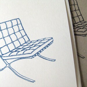 May include: A blue line drawing of a modern chair with a grid-patterned seat and a curved, metal frame. The chair is set against a white background, with a partial view of a similar chair in the background.