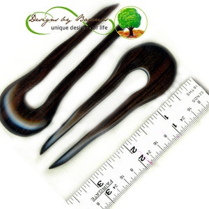 May include: Three dark brown wooden hair forks with a U-shaped design. The forks have a smooth finish and a gradient of colors, including blue and white. A ruler is placed next to the forks. The image includes the text "Designs by Bareesa unique designs for life."