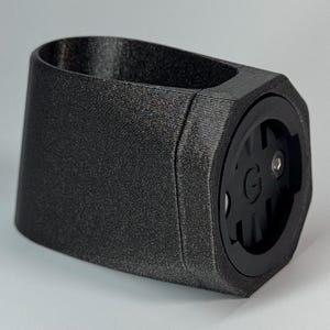 Könnte beinhalten: Schwarzer 3D-gedruckter Fahrradhalter mit einem schwarzen Garmin-Halter aus Kunststoff. Der Garmin-Halter hat eine schwarze Schraube aus Kunststoff.