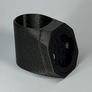 Könnte beinhalten: Ein schwarzer 3D-gedruckter Fahrradhalter mit einer GoPro-Halterung an der Seite. Die Halterung ist so konzipiert, dass sie an einem Lenker oder einem anderen Fahrradteil befestigt werden kann.