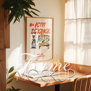 Puede incluir: Una impresión enmarcada con una ilustración vintage de una máquina de café y el texto "Mon Petit Dejeuner" en rojo y amarillo. La impresión está colgada en una pared con una mesa de madera y una jarra de vidrio de jugo de naranja en frente.