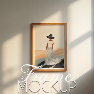 May include: A framed art print featuring a woman in a hat and striped skirt, standing on a hillside. The artwork is in a wooden frame, and the image has a neutral color palette with beige, black, and white tones. The text "Frame MOCKUP" is at the bottom.