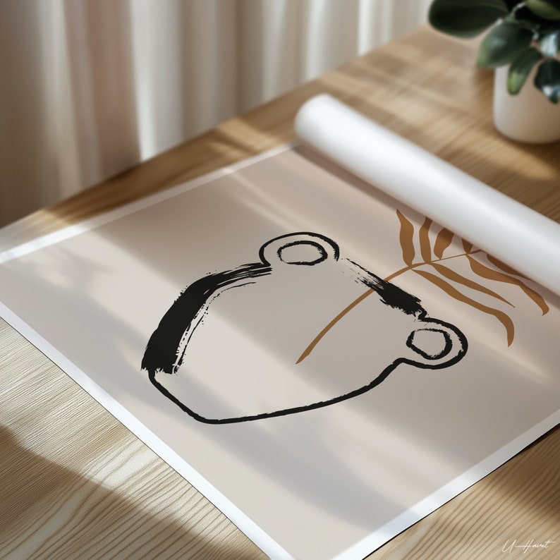 May include: An abstract art print featuring a black brushstroke design of a vase with a brown stem and leaf on a beige background. The print is partially rolled up, resting on a wooden surface, with a white roll of paper and a potted plant in the background.