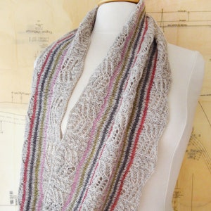 May include: A beige knitted scarf with a lacy pattern and stripes of pink, red, green, and gray.