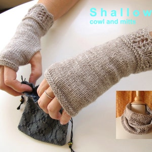 May include: A pair of beige knitted fingerless mitts with a delicate lace pattern at the wrist. The mitts are shown being held by a person. The image also shows a beige knitted cowl with a similar lace pattern. The text "Shallows cowl and mitts" is displayed above the mitts.