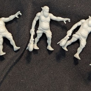 May include: Six gray plastic figurines of fantasy creatures, possibly goblins or orcs, with exaggerated features and holding small bags or pouches.