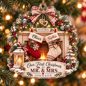 Könnte beinhalten: Ein Weihnachtsschmuck mit Kaminmotiv, zwei Strümpfen mit den Namen Oliver und Sophia, einer Laterne, einem kleinen Baum und einem Schild mit der Aufschrift 09.15.2026 und Our First Christmas as MR. & MRS. JOHNSON, verziert mit Tannenzweigen und Beeren.