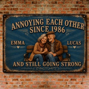 K&ouml;nnte beinhalten: Ein rechteckiges Metallschild mit blauem Hintergrund, das ein Paar auf einer Bank zeigt. Der Text lautet: ANNOYING EACH OTHER SINCE 1986, EMMA, LUCAS, AND STILL GOING STRONG. Das Schild hat einen abgenutzten Rosteffekt an den R&auml;ndern und Herzsymbole.