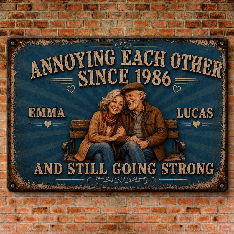 K&ouml;nnte beinhalten: Ein rechteckiges Metallschild mit blauem Hintergrund, das ein Paar auf einer Bank zeigt. Der Text lautet: ANNOYING EACH OTHER SINCE 1986, EMMA, LUCAS, AND STILL GOING STRONG. Das Schild hat einen abgenutzten Rosteffekt an den R&auml;ndern und Herzsymbole.