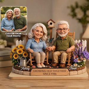 May include: A custom figurine set featuring an older couple sitting in rocking chairs. The woman wears a blue shirt and the man wears a green shirt and glasses. The base includes sunflowers, a watering can, butterflies, and the text "GROWING OLD TOGETHER SINCE 1986" with the names "Ashley" and "Noah".