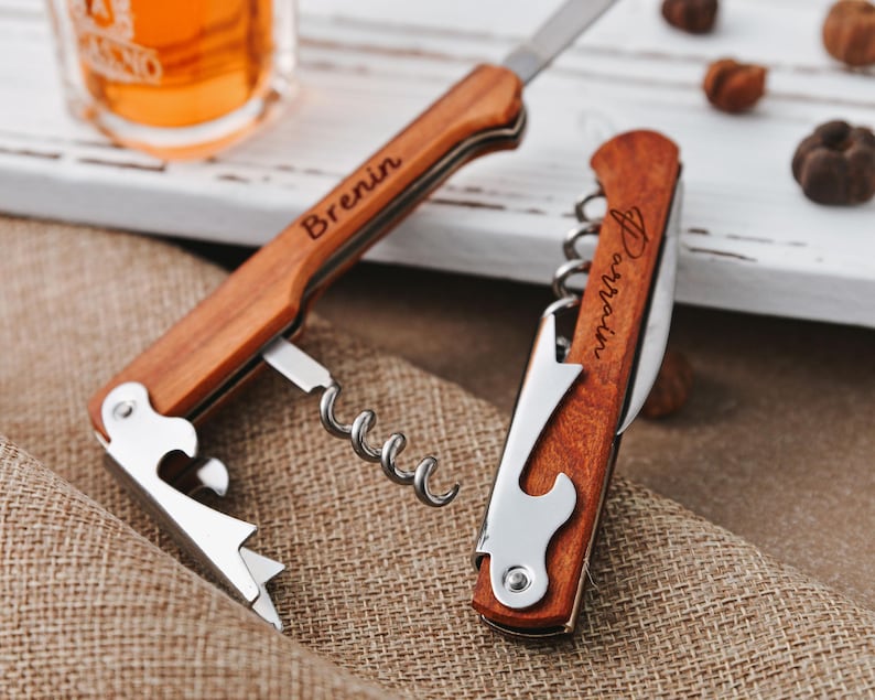 May include: A wooden bottle opener with a corkscrew, bottle opener, and knife. The opener is engraved with the name "Brenin".