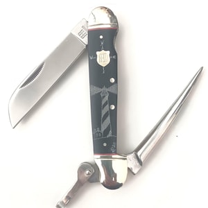 May include: A multi-tool pocket knife with a black handle featuring a lighthouse design. The knife has a silver blade, a pointed tool, and a bottle opener. The handle has a red accent and a silver end cap.