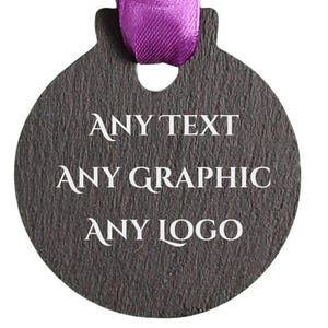 May include: A dark grey, round tag with the words "ANY TEXT, ANY GRAPHIC, ANY LOGO" in white. A purple ribbon is attached at the top. The tag has a textured surface.