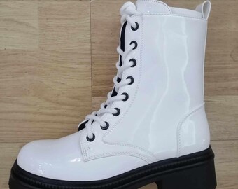 Puede incluir: Botas blancas de cuero con cordones y suela de plataforma negra.