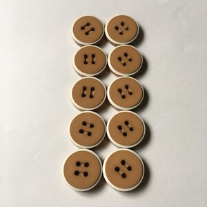 May include: Ten brown buttons with a white border. Each button has two holes.