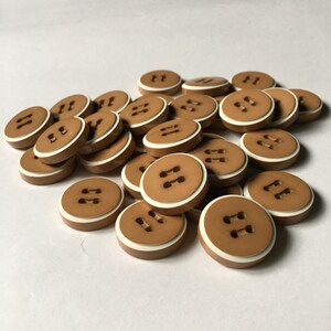 May include: A pile of brown plastic buttons with a white rim and two white holes in the center.