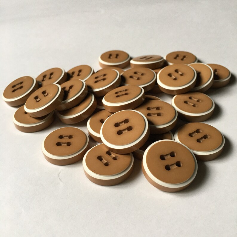 May include: A pile of brown plastic buttons with a white rim and two white holes in the center.