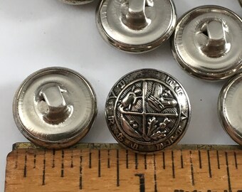 May include: Silver metal buttons with a design of a four-leaf clover, a boot, a bird, and a fish. The buttons are approximately 1 inch in diameter.