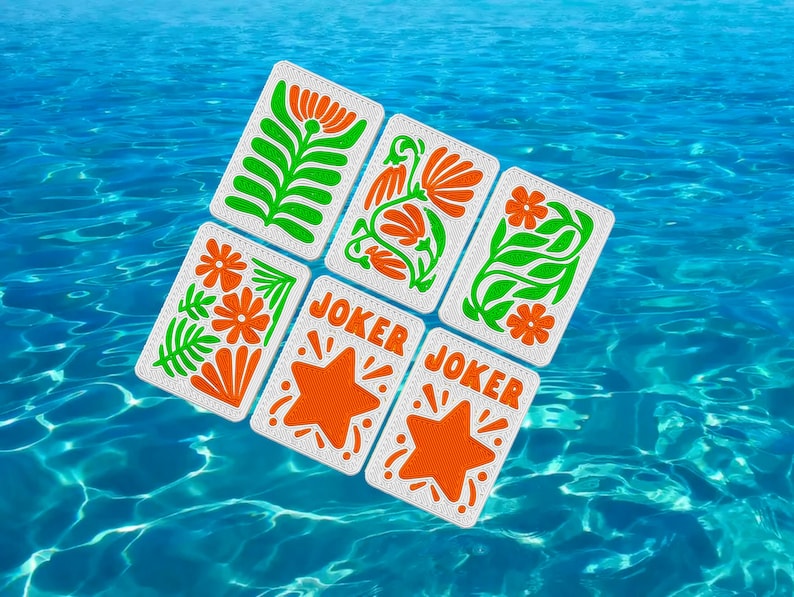 May include: Six playing cards with floral designs in orange and green, and two cards with orange starbursts and the word "JOKER". The cards are set against a backdrop of blue water.
