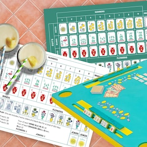 Puede incluir: Un juego de Mahjong turquesa y amarillo con fichas, tableros y dos cócteles con adornos de piña. Los tableros muestran símbolos de palos, números y flores. El juego incluye 152 fichas.
