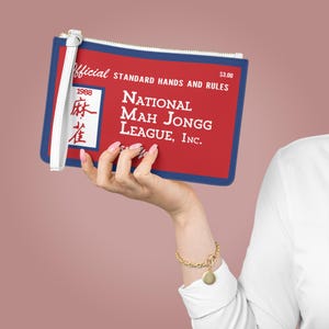 May include: A red and blue clutch with the text "Official Standard Hands and Rules" and "National Mah Jongg League, Inc." printed on it. The clutch has a white wrist strap and a zipper. The year 1988 is printed on the clutch.