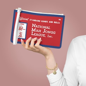 May include: A red and blue clutch with the text "NATIONAL MAH JONGG LEAGUE, INC." and "STANDARD HANDS AND RULES." The clutch has a white wrist strap and a zipper. The year "1966" is printed on the clutch.