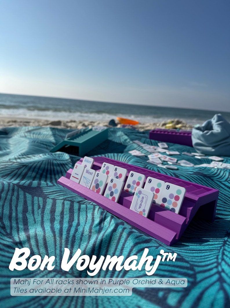May include: A purple plastic rack holding white game tiles with colorful circular patterns and text including Joker, West, and Soap. A teal rack sits nearby. The text Bon Voymahj and Mahj For All racks shown in Purple Orchid & Aqua Tiles available at MiniMahjer.com is visible.