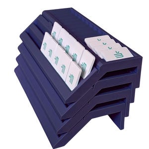 May include: A dark blue tiered display rack with multiple horizontal slots holding several white rectangular tiles. Each tile features a small green graphic of a stylized letter M with a leaf icon above it, arranged in organized rows.
