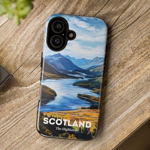 Może przedstawiać: Etui na telefon z krajobrazem Szkocji, z jeziorem, górami i błękitnym niebem. Na etui znajduje się napis "SCOTLAND" i "The Highlands". Etui leży na drewnianej powierzchni.