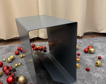 May include: A gray metal stand with a rectangular shape and a curved opening. The stand is on a gray carpet with red and gold ornaments scattered around it.