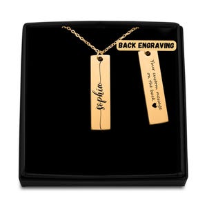 May include: Gold necklace with two rectangular pendants. The front pendant is engraved with the name "Sophia". The back pendant has the text "Your custom message on the back" and a heart symbol.  BACK ENGRAVING is written on a small tag.
