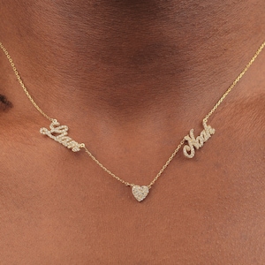 Könnte beinhalten: Eine goldene Halskette mit zwei Namen, "Liam" und "Noah", die in Diamanten geschrieben sind, und einem kleinen Diamanten-Herz-Anhänger.