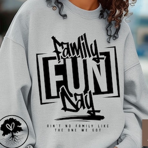 Puede incluir: Sudadera gris claro con la frase "Family Fun Day" en negro. El diseño incluye un gráfico de árbol y el texto "Ain't no family like the one we got". Descarga digital.