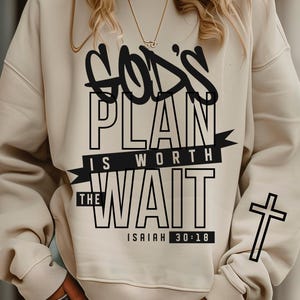 May include: Cream-colored sweatshirt with the text "GOD'S PLAN IS WORTH THE WAIT" in black, along with a cross on the sleeve. The sweatshirt also features the Bible verse Isaiah 30:18. The design is a digital download.