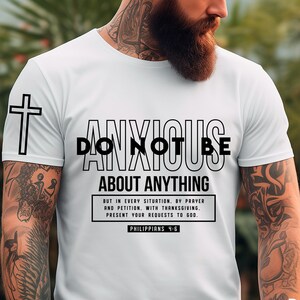 Pode incluir: Camiseta branca com o texto preto "DO NOT BE ANXIOUS ABOUT ANYTHING" e uma cruz na manga esquerda. A camiseta também inclui o versículo bíblico Filipenses 4:6. Disponível para download digital.