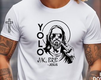May include: A white t-shirt with a black and white illustration of Jesus wearing sunglasses and making a peace sign. The text "YOLO" is written vertically above Jesus's head, and the text "J/K, BRB -JESUS" is written below him.