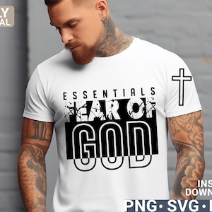 Op de afbeelding: Wit T-shirt met zwarte tekst die "Essentials Fear of God" luidt, met een zwart-witte kruisafbeelding op de rechtermouw.
