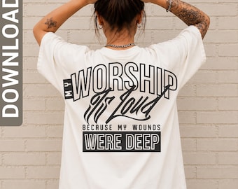 May include: An off-white short-sleeve t-shirt featuring black text on the back that reads: MY WORSHIP IS LOUD BECAUSE MY WOUNDS WERE DEEP. The design uses a mix of bold block lettering and stylized script fonts to display the message clearly.