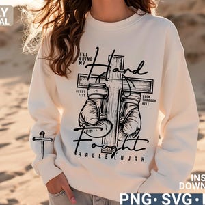 May include: Cream-colored sweatshirt with a black graphic of boxing gloves on a cross, with the words "I'll bring my hand fought hallelujah". A small cross is on the left sleeve. The words "Only Digital Download" are on the top left.