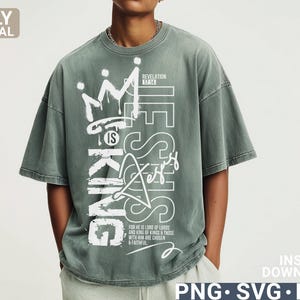 Puede incluir: Una camiseta verde salvia con el texto "JESUS IS KING" en blanco, con un estilo de grafiti. La camiseta tambi&eacute;n presenta un gr&aacute;fico de corona y las palabras "REVELATION 17:14" y "FOR HE IS LORD OF LORDS AND KING OF KINGS & THOSE WITH HIM ARE CHOSEN & FAITHFUL."