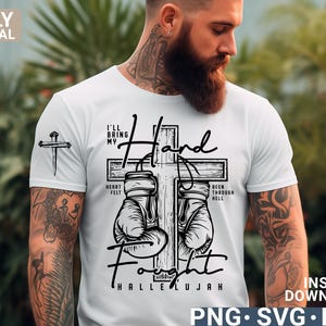 May include: White t-shirt with a graphic design featuring a cross, boxing gloves, and the words "I'll Bring My Hand Fight" and "Hallelujah". The shirt also has a small cross graphic on the sleeve.