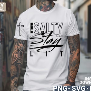 May include: White t-shirt with the text "BE SALTY Stay LIT" in black. The design includes a cross and the scripture reference "5:13-14" and "MATT". The shirt is a digital download in PNG, SVG, and EPS formats.