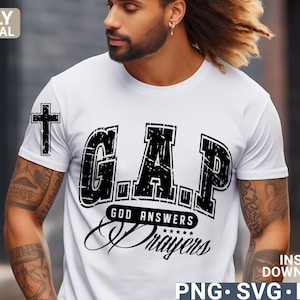 May include: A white t-shirt with a black graphic that says "GAP" with the words "GOD ANSWERS PRAYERS" underneath. The graphic is in a distressed font style.